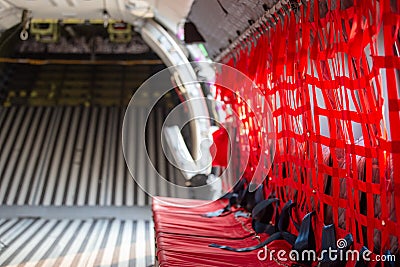 red seat with seatbelt for paratrooper or airborn forces in military transport aircraft cabin Stock Photo