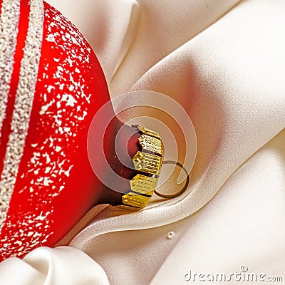 Red shiny christmas toy lies on a white silk cloth.. Christmas decorations and a red ribbon bow isolated on white. Hanging balls, Stock Photo