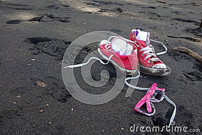 Red shoes and girls sunglasses on Waipio Valley black sand beach, Hawaii Stock Photo