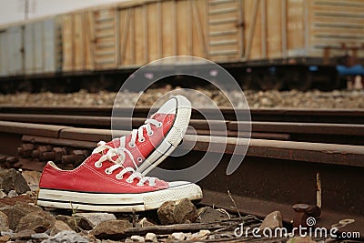 Red shoes leaning on the train tracks. Stock Photo