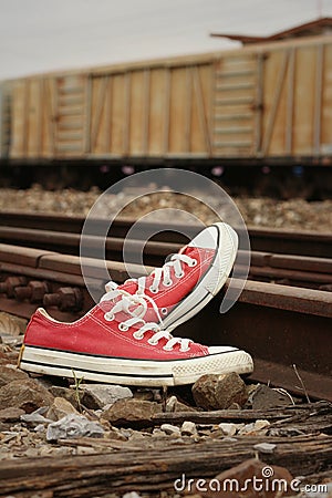 Red shoes leaning on the train tracks. Stock Photo