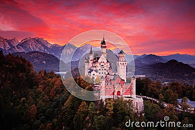 Neuschwanstein fairy tale castle. Beautiful sunset view of the bloody clouds with autumn colours in trees, twilight night, Bavaria Stock Photo