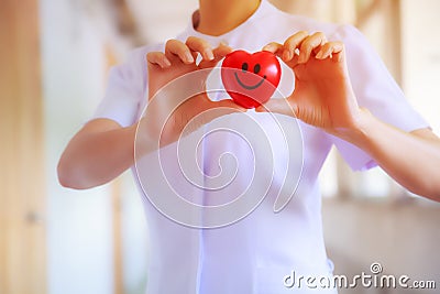 Red smiling heart held by female nurse`s hand, representing giving effort high quality service mind to patient. Professional, Spec Stock Photo