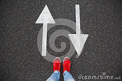 Red sneakers on the asphalt road with drawn arrows pointing to two directions Stock Photo