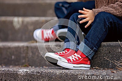 Red sneakers on a kids feet, sitting on stairs Stock Photo