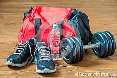 Red sports bag and sneakers near a heavy dumbbell Stock Photo