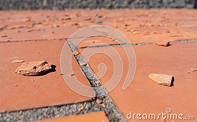 Red square floor tiles damaged by weathering or material defects. The surface is crumbling and the plates are disintegrating. Stock Photo