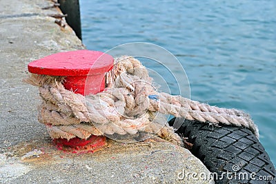 Red stand on the pier with a rope and tyre Stock Photo