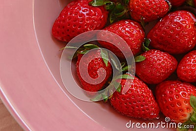 Red strawberies of the different size on the plate Stock Photo