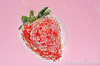 Red strawberry fruit floating in the water on pink background. High value commercial food photography. Fresh beverage in menu. Stock Photo