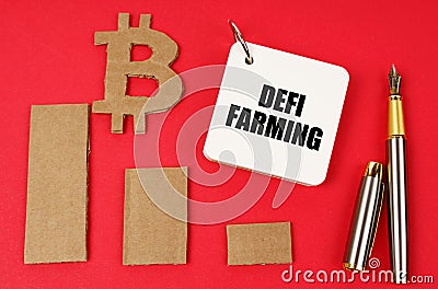 On a red surface lie the bitcoin symbol, a pen and a notepad with the inscription - DEFI farming Stock Photo