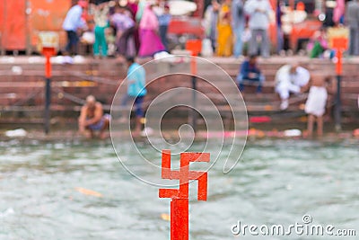 Red swastika cross on the Ganges River at Haridwar, India, sacred city for Hindu Religion. Pilgrims bathing on the ghats. Stock Photo