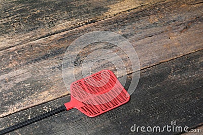 Red swatter fly, object made of plastic on Wood floor background Stock Photo