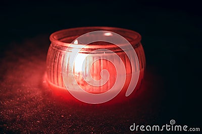 Red textured candle with flame in the snow during darkness Stock Photo