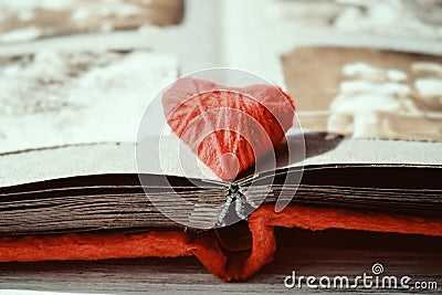 Red thread heart on open photo album on wooden table background. Vintage book or photo album with thread heart Stock Photo