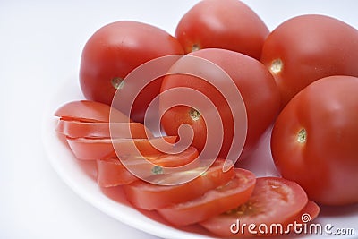 Red tomatoes on a white plate. Sliced tomatoes on a white background. Vegetables on a plate Stock Photo