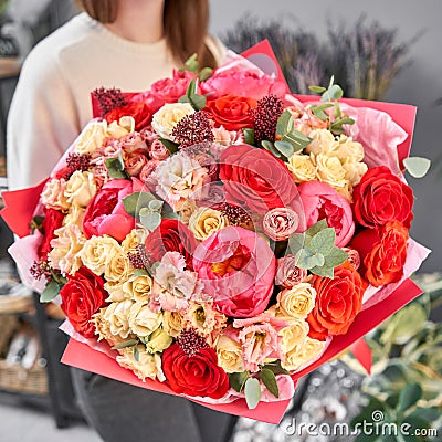 Red tones Beautiful bouquet of mixed flowers in womans hands. the work of the florist at a flower shop. Handsome fresh Stock Photo