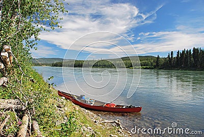 Red towed and abandoned canoe on Yukon River Stock Photo