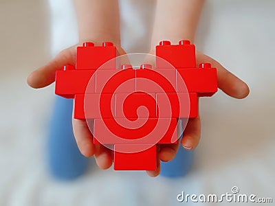 Red toy blocks heart on childs hands. Editorial Stock Photo