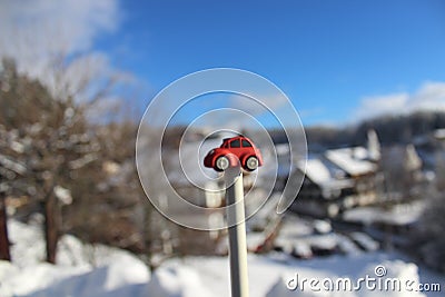 Red toy car infront of snowy town / landscape with blue sky Stock Photo