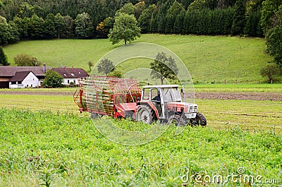 Red tractor in the field near house Stock Photo