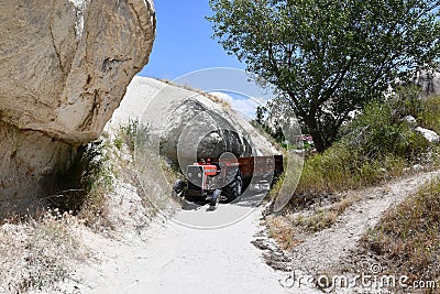Red tractor on a narrow sandy path between rocks in the countryside in Cappadocia, Turkey Editorial Stock Photo