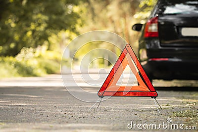 Red triangle, red emergency stop sign and black car with technical problems in the blurred background. Emergency stop of the car Stock Photo