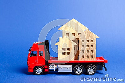 Red truck transports wooden houses. Concept of transportation and cargo shipping, moving company. Construction of new houses Stock Photo