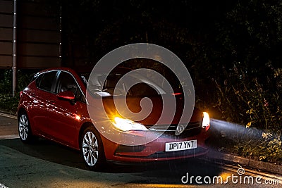The red Vauxhall Astra car waiting on the side of the road in the night rain waiting for a help with flashing warning lights Editorial Stock Photo