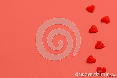 Red velure texture heart candies scattered on coral background. Border frame arrangement. Valentine romance mother`s day charity Stock Photo