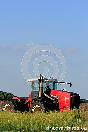 A Red Versatile Tractor in a farm field with blue sky and clouds Editorial Stock Photo