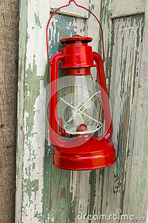 Red vintage handle gas lantern on rustic wooden wall. Stock Photo