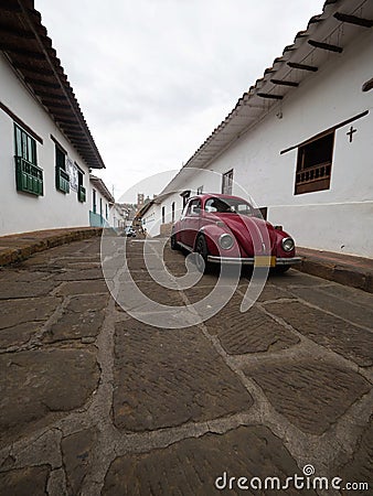 Red vintage retro VW Volkswagen Beetle car vehicle parked in streets road of historic town center Barichara Colombia Stock Photo