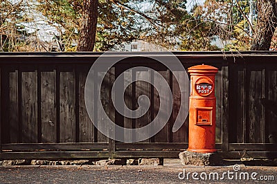 Red vintgae Japanese mail letter postbox and black wooden wall Editorial Stock Photo