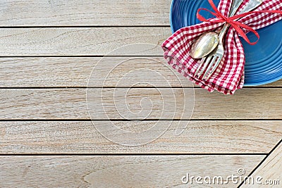 A Red White and Blue Picnic Table Place Setting with napkin, fork and spoon and plate in an upper corner on horizontal wood board Stock Photo