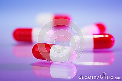 Red and white capsules (bolus) on violet Stock Photo