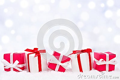 Red and white Christmas gifts in snow with twinkling background Stock Photo