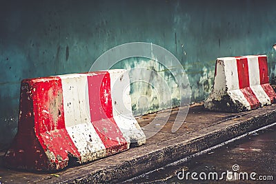 Red white concret barrier stop going sign on street stand on footpath green painted old wall background Stock Photo