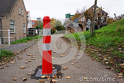 Red and white dividing post. Road barrier to separate the footpath from cyclists who belong on the bike path. Editorial Stock Photo