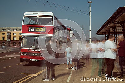 Red and White double decker Leyland Olympian preserved bus at bus stop. Ghostly blurred passengers wait to board and travel Editorial Stock Photo
