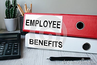 Red and white folders with documents lying on the desktop next to a calculator and a pen. The lettering on the folder has Stock Photo