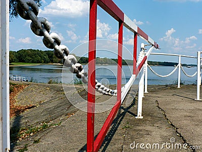 red and white with heavy chain and gate in diminishing perspective at a river side Stock Photo