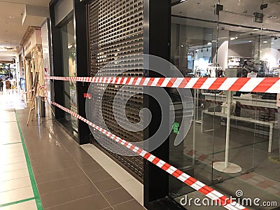 red and white tape over closed shop entrance in mall. Restrictions due to covid pandemic Editorial Stock Photo