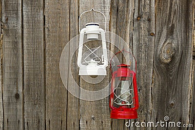 Red and white vintage handle gas lanterns on rustic wooden wall. Stock Photo