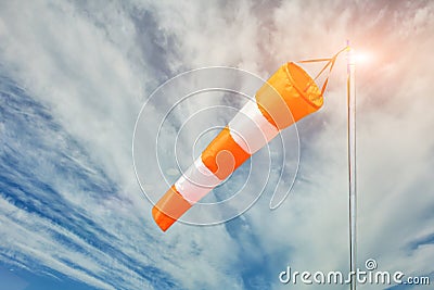 Red and white wind sock on blue sky and clouds background Stock Photo