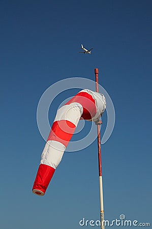 Red and white windsock with airplane to the rear. Stock Photo