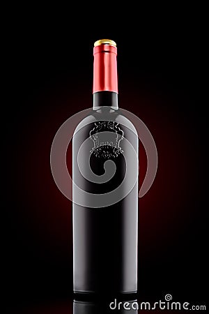 Red wine bottle with emboss at the black background with red spot Stock Photo