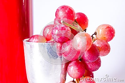 A red wine bottle, grapes and a silver cup Stock Photo