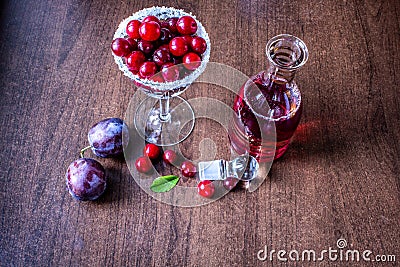 Red wine in a decanter. cherry in a glass. plum on the table Stock Photo