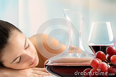 Red wine decanter and grapes with woman in background. Stock Photo